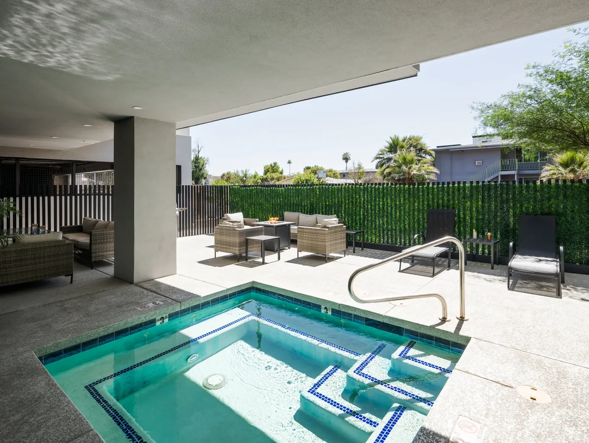 An inviting communal swimming pool surrounded by lounge chairs and lush greenery. The warm glow of sunset casts a romantic light across the area, creating a scene perfect for unwinding together after a day of exploring.
